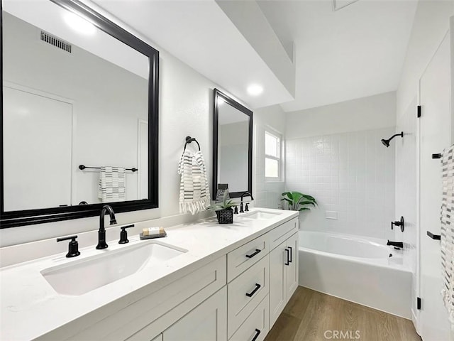 full bath featuring washtub / shower combination, wood finished floors, a sink, and visible vents