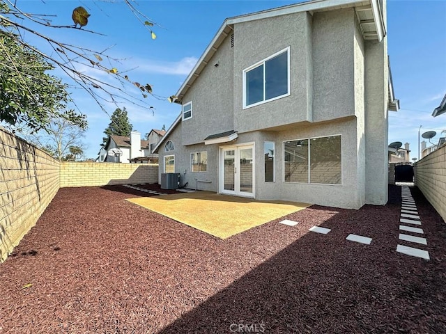 rear view of house featuring a fenced backyard, a patio, central AC, and stucco siding