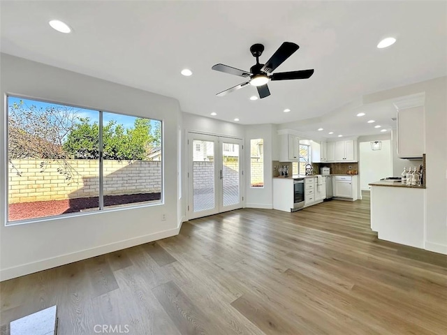 unfurnished living room featuring light wood-type flooring, french doors, and baseboards