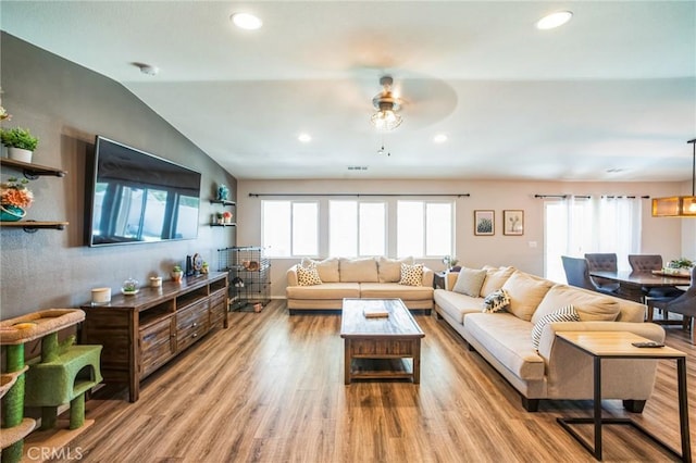 living area with lofted ceiling, a wealth of natural light, wood finished floors, and recessed lighting