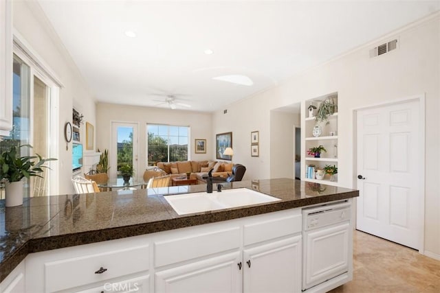 kitchen featuring white dishwasher, white cabinetry, open floor plan, and a sink