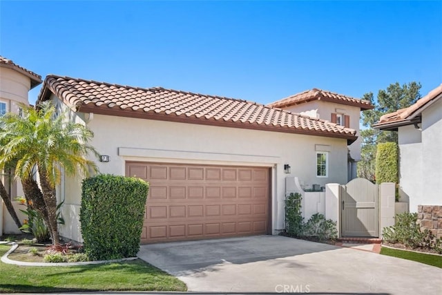 mediterranean / spanish home featuring an attached garage, a tile roof, a gate, and stucco siding