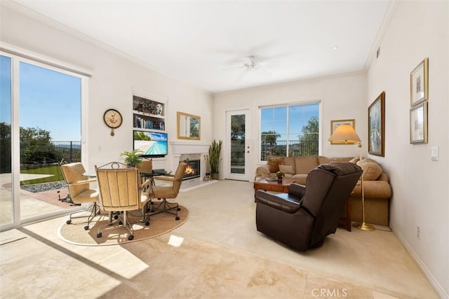 sitting room featuring a warm lit fireplace, baseboards, ceiling fan, crown molding, and built in shelves