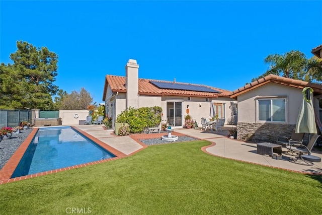 back of house with a fenced in pool, a patio, a fenced backyard, a chimney, and roof mounted solar panels