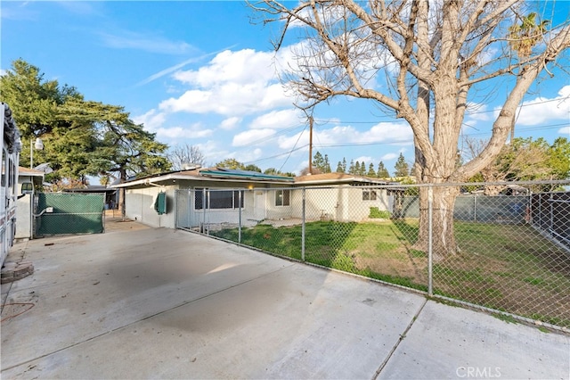 view of front of home with solar panels, a front lawn, fence, and a gate