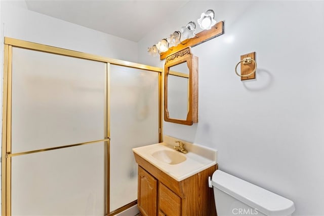 bathroom featuring toilet, a shower stall, and vanity