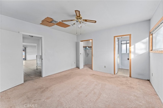 unfurnished bedroom featuring a spacious closet, carpet flooring, a ceiling fan, and connected bathroom