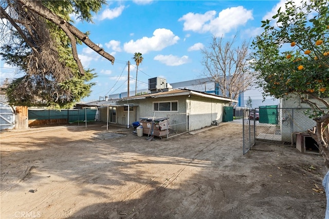 back of house featuring cooling unit, a gate, fence, and stucco siding