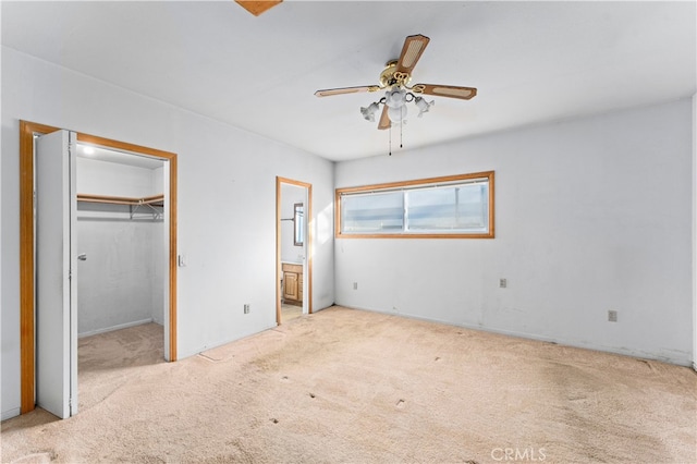 unfurnished bedroom with a closet, a spacious closet, ensuite bathroom, a ceiling fan, and carpet flooring