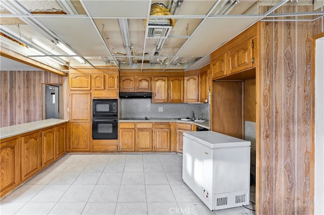 kitchen with under cabinet range hood, a sink, visible vents, black appliances, and brown cabinetry