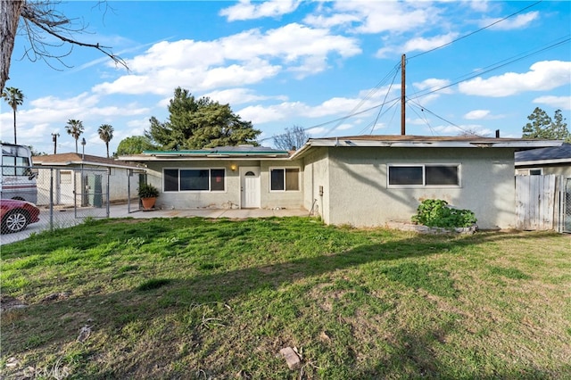 single story home featuring fence, a patio area, roof mounted solar panels, a front lawn, and stucco siding