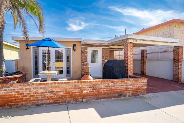 view of front facade featuring driveway, french doors, and fence