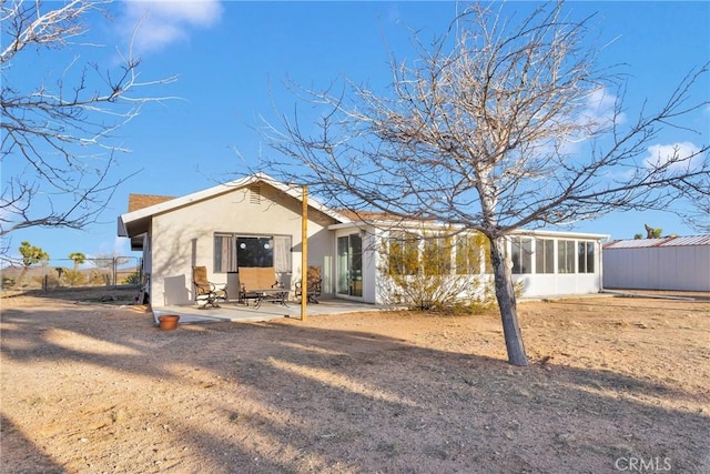 rear view of property featuring a sunroom, stucco siding, and a patio