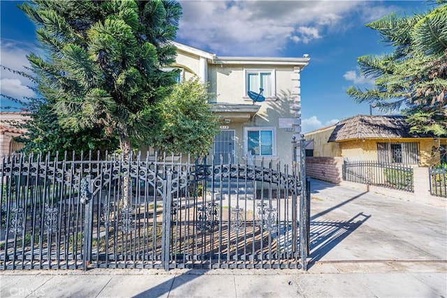 view of front of home featuring a fenced front yard, a gate, and stucco siding