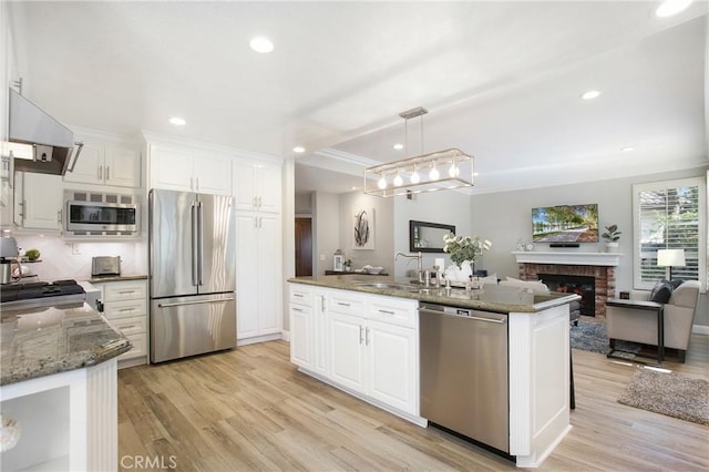 kitchen with open floor plan, stainless steel appliances, a kitchen island with sink, and white cabinetry