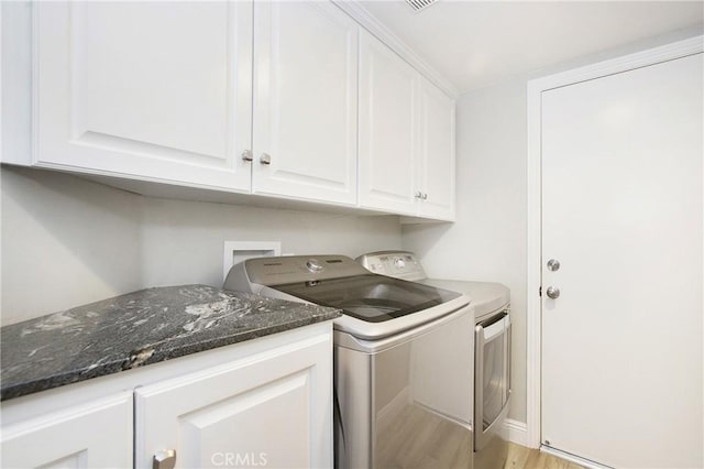 washroom with light wood-style flooring, washing machine and clothes dryer, and cabinet space