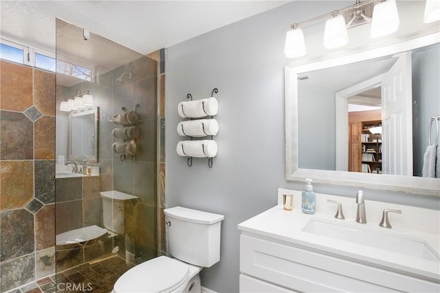 full bathroom featuring vanity, a tile shower, and toilet