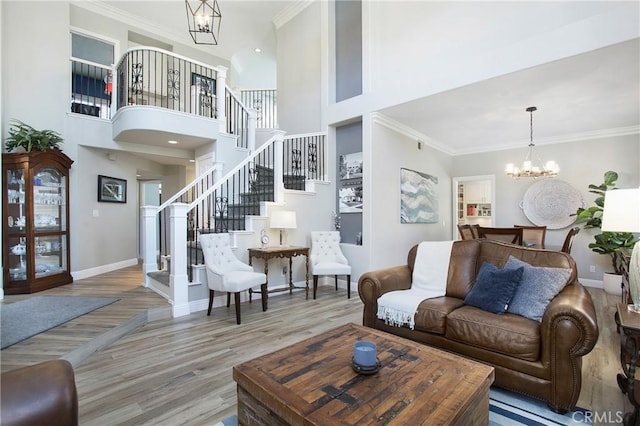 living area featuring crown molding, a notable chandelier, stairway, and wood finished floors