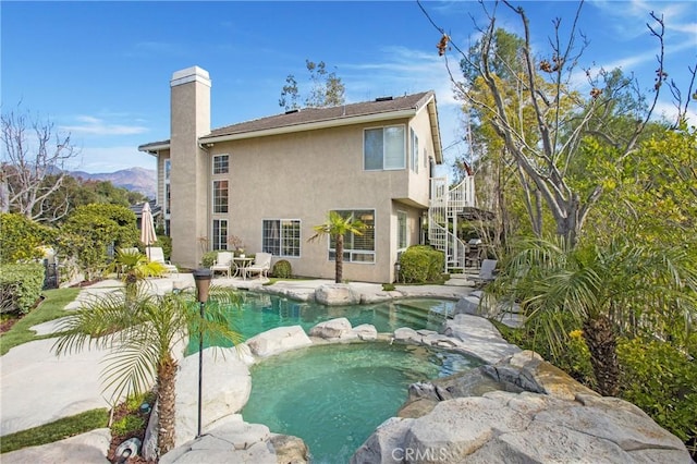 view of swimming pool with a pool with connected hot tub, a patio area, a mountain view, and stairs