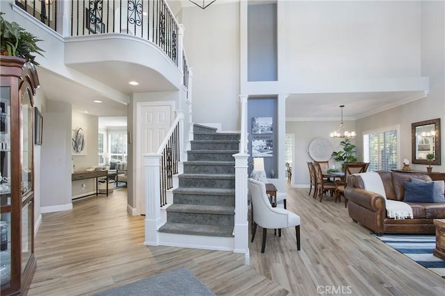 stairs featuring an inviting chandelier, crown molding, baseboards, and wood finished floors