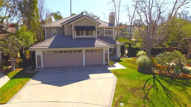 view of front of house featuring a chimney, a garage, driveway, a tiled roof, and a front lawn