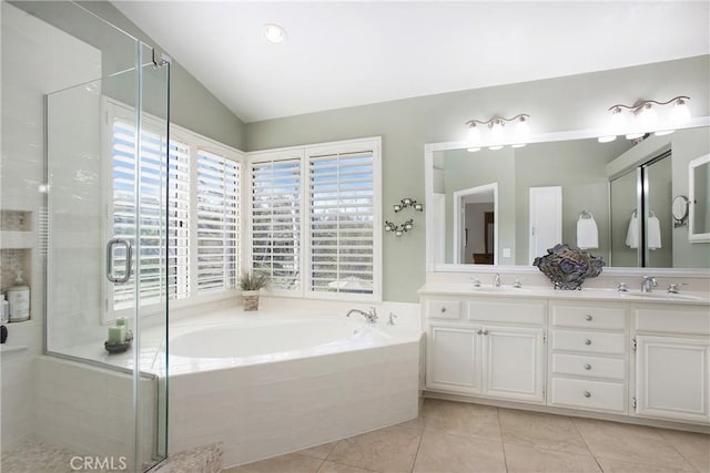 full bathroom with a garden tub, a shower stall, vaulted ceiling, and a sink