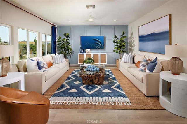 living area with light wood finished floors, visible vents, and a ceiling fan