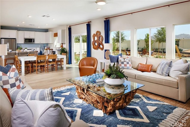 living room featuring light wood-type flooring, visible vents, and recessed lighting