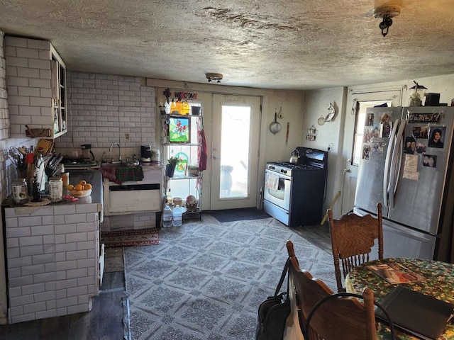 kitchen featuring concrete block wall, dark floors, stainless steel appliances, a textured ceiling, and french doors