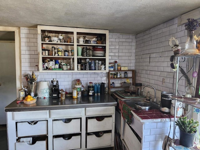 bar with a sink, backsplash, and a textured ceiling