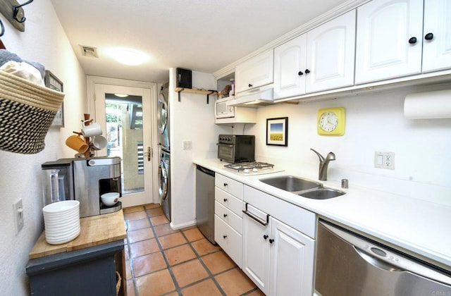 kitchen with dishwasher, light countertops, stacked washing maching and dryer, and white cabinetry