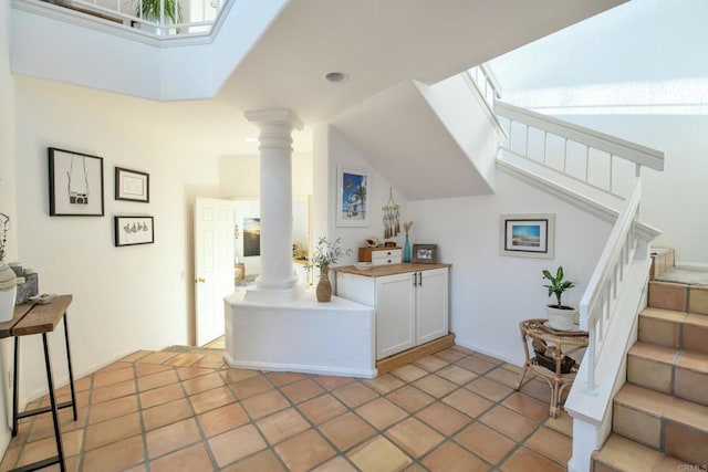 interior space featuring a skylight, decorative columns, white cabinetry, and light countertops