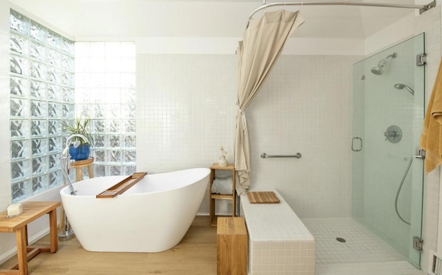 full bathroom featuring wood finished floors, a stall shower, and a freestanding tub