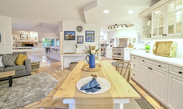 interior space with recessed lighting, white cabinetry, open floor plan, stainless steel range, and glass insert cabinets