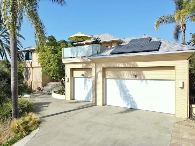 view of front of property with a garage, roof mounted solar panels, and roof with shingles