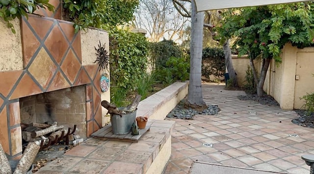 view of patio with fence and exterior fireplace