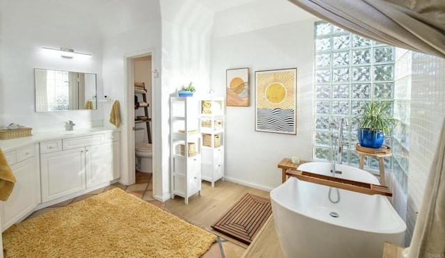 bathroom featuring a freestanding bath, vanity, toilet, and wood finished floors