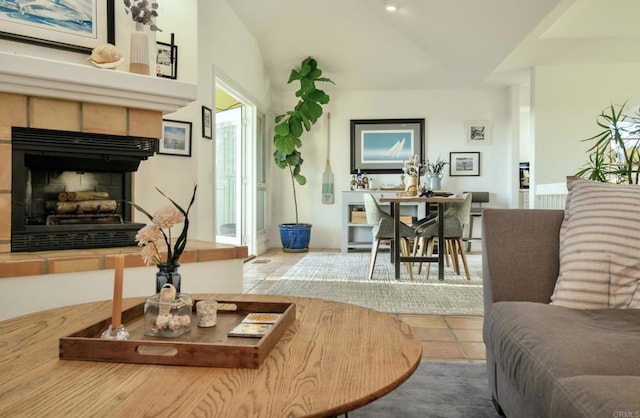 living room featuring tile patterned flooring, vaulted ceiling, and a tiled fireplace