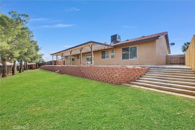 rear view of house featuring fence private yard, stucco siding, a yard, and central AC unit