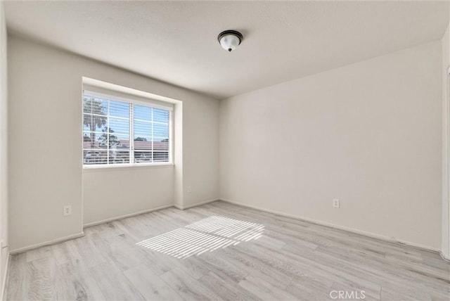 spare room featuring light wood-style flooring and baseboards