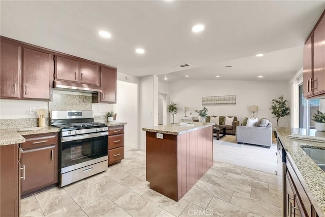 kitchen featuring under cabinet range hood, visible vents, open floor plan, light stone countertops, and gas stove