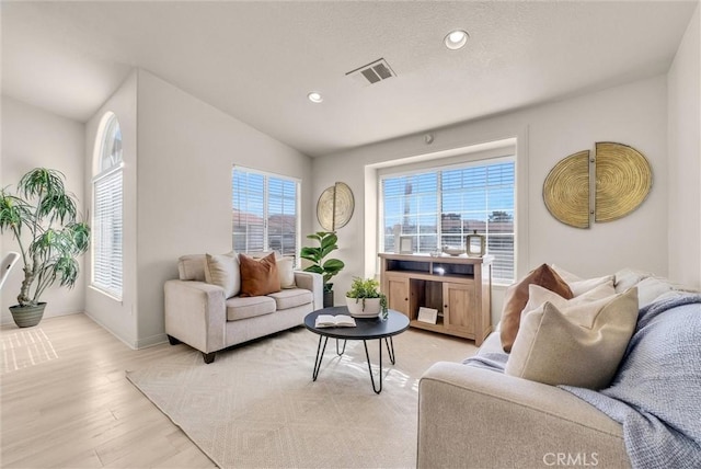 living area featuring baseboards, visible vents, lofted ceiling, light wood-style floors, and recessed lighting