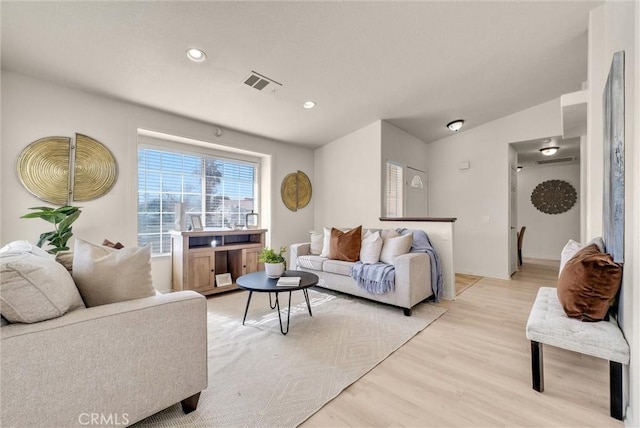 living area featuring recessed lighting, visible vents, vaulted ceiling, and light wood finished floors