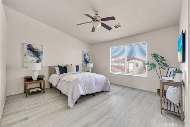 bedroom featuring lofted ceiling, ceiling fan, visible vents, and light wood-style floors