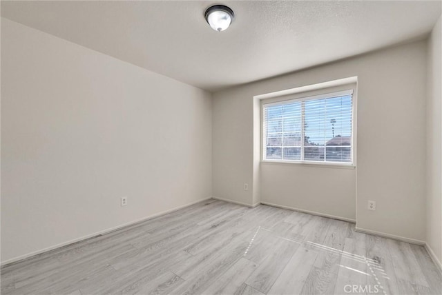 spare room with light wood-style floors and baseboards