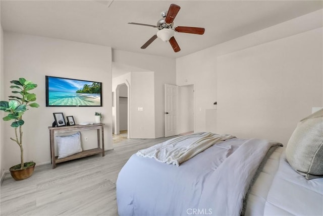 bedroom featuring arched walkways, ceiling fan, and light wood-style flooring