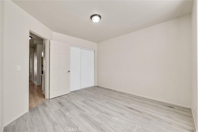 unfurnished bedroom featuring a closet and light wood-style flooring