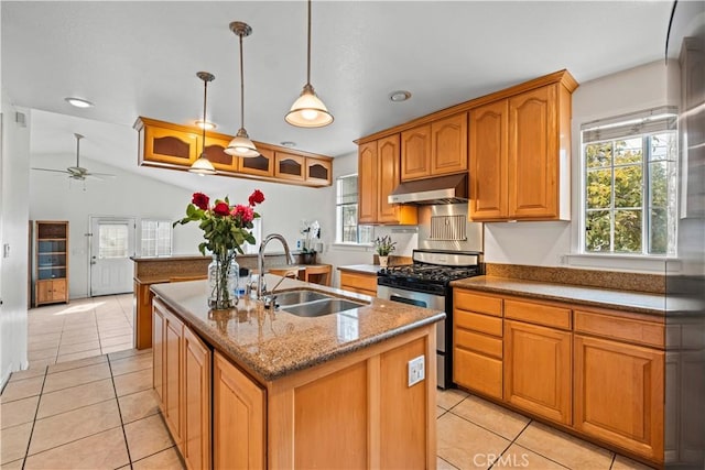 kitchen featuring light tile patterned floors, a kitchen island with sink, under cabinet range hood, a sink, and gas range