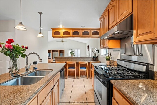 kitchen featuring stone countertops, range with gas stovetop, under cabinet range hood, a sink, and light tile patterned flooring