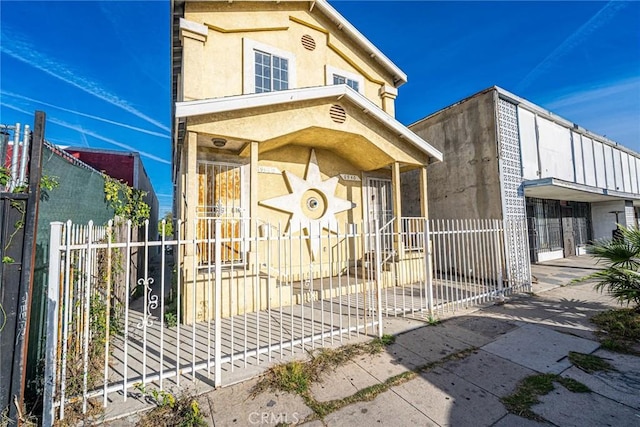 exterior space featuring a fenced front yard, a gate, and stucco siding